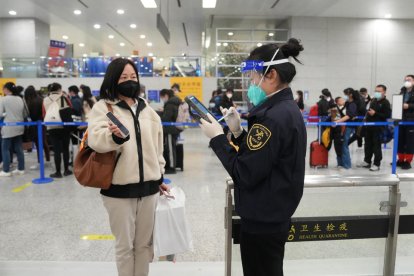 Un trabajador del aeropuerto de Pekín revisa la documentación de una viajera el pasado domingo. 