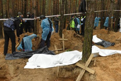 Treballadors exhumant els cossos a la fossa comuna trobada a la ciutat d’Izium.