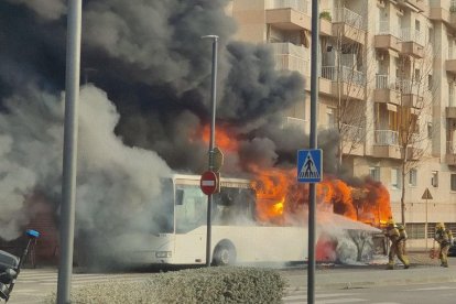 Els bombers proven de sufocar les flames de l’autobús.