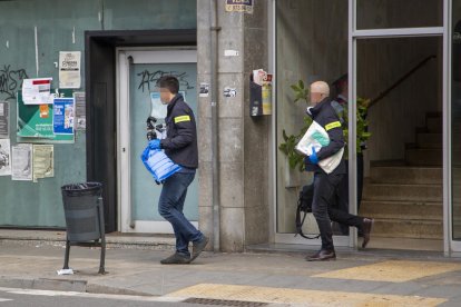 Dos agentes de los Mossos saliendo del número 80 de la avenida Alcalde Porqueres, donde fue hallado el cadáver.