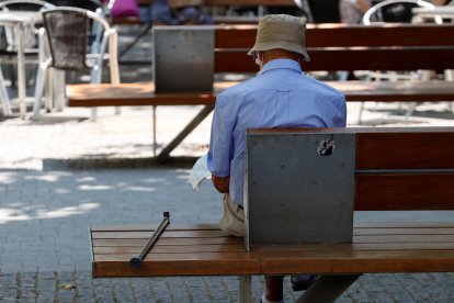 Imatge d’un jubilat assegut en un banc d’un parc.