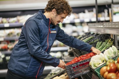 Un treballadors de la cadena de supermercats Aldi en una imatge amb aliments i fruites