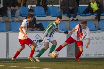 Un jugador de l’Alguaire controla l’esfèric davant de la pressió de dos defenses del Torrefarrera.