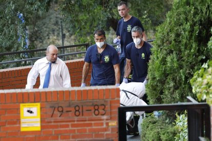 Bomberos y servicios funerarios retiran el cuerpo de uno de los dos fallecidos en el inmueble.