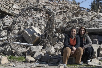 Dos mujeres sentadas frente a los escombros de una casa en el centro de la aldea turca de Ordekdede.