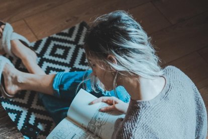 Imagen de archivo de una persona sentada leyendo en el suelo.