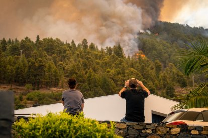 Uns veïns observen com el foc corre turó a baix sense control.