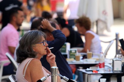 Una dóna fumant en una terrassa.