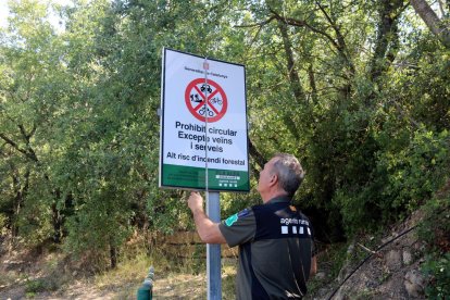 Un Agent Rural obre un cartell de prohibició del pas al Montsec a la zona de Corçà, a Àger, per l'activació del pla Alfa 3.