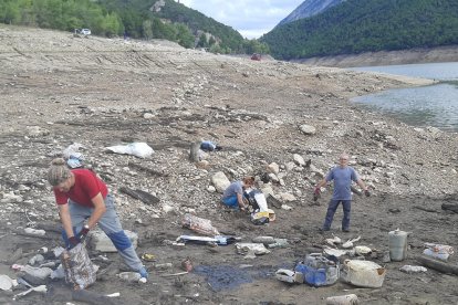 Voluntaris recollint escombraries al llit del pantà d’Oliana.