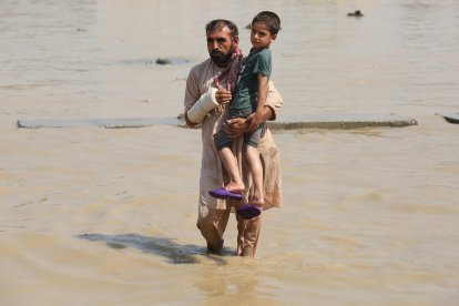 Un hombre sostiene a un niño en una zona inundada.