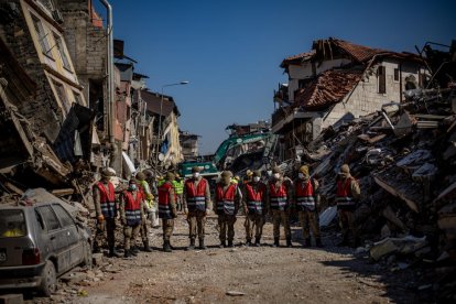 Un equip de rescat camina entre edificis enderrocats pels sismes a Antioquia, Turquia.