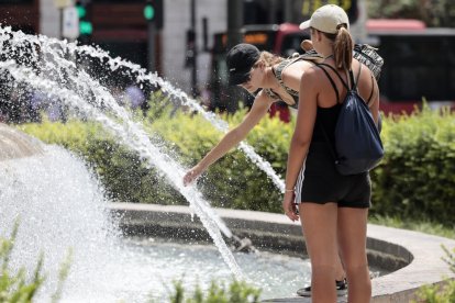 Dos dones refrescant-se en una font a València.