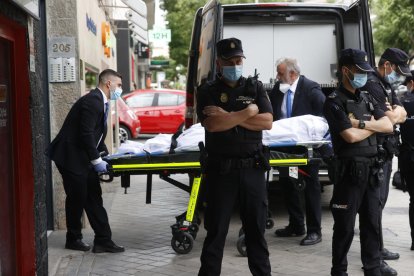 Miembros del servicio funerario trasladan un cadáver de la vivienda sita en el número 205 de la calle Serrano de Madrid, donde este lunes dos mujeres y un hombre de edad adulta han muerto tiroteados.