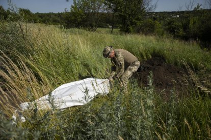 Un militar ucraïnès exhuma cossos de soldats russos a Khàrkiv.