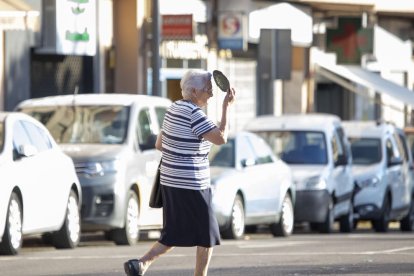 Una mujer se protege del sol mientras cruza la calle en Lleida. 