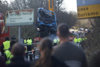 Una grua col·loca l’autobús accidentat sobre el pont.