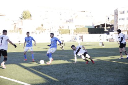 Un jugador de l’Alcarràs avança amb la pilota després de deixar enrere un defensor.