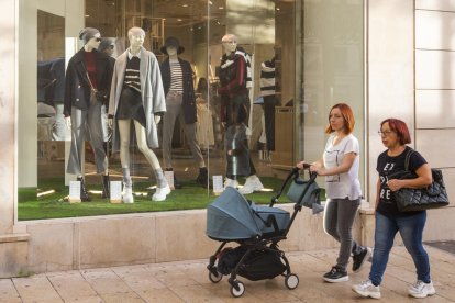 Passejants en màniga curta, ahir davant d’un aparador amb roba de tardor.