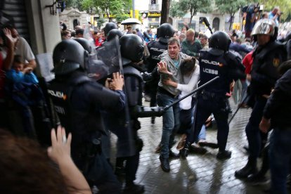 Un hombre intenta proteger a una mujer de los porrazos de agentes antidisturbios de la policía española el 1 de octubre de 2017.