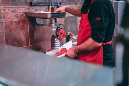 Un operari preparant  carn picada en una imatge d'arxiu.