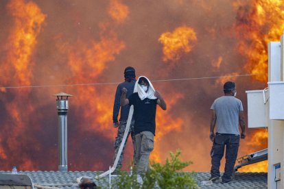 Los residentes se protegen en los techos de sus casas frente a las llamas en Gennadi, en la isla de Rodas.