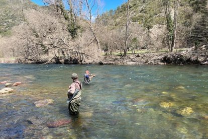 Un pescador pescant sota l'atenta mirada d'un jutge de la competició esportiva de pesca modalitat mosca.