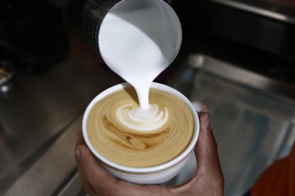 Fotografia d'arxiu d'un home preparant una tassa de cafè amb llet.