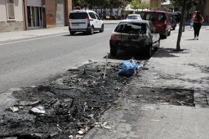 Contenedores calcinados y un coche dañado por el fuego en la calle Antoni Solé. 