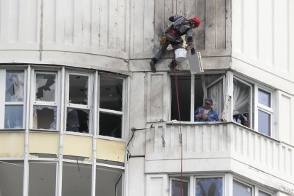 Dos treballadors reparen un edifici residencial afectat per l’atac a Moscou.