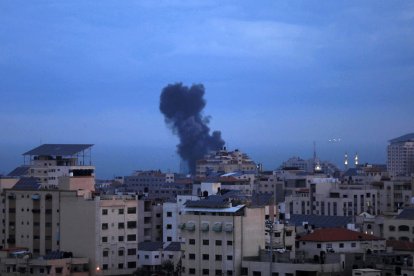 Fum provocat per míssils emergeix entre edificis a Gaza.