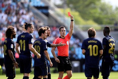 Xavier Estrada Fernández muestra una tarjeta roja a un jugador del Real Madrid.