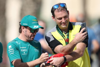 Fernando Alonso firma un autógrafo a un operario del circuito.