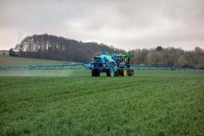 Un tractor ruixant fertilitzants sobre un camp en una imatge d’arxiu.