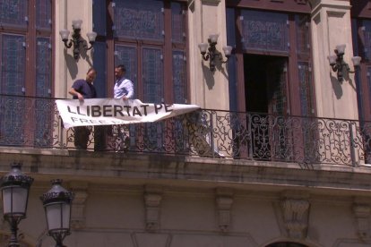 A dalt, el moment de retirada de la pancarta del balcó que dona a Blondel, i a baix, ja sense.