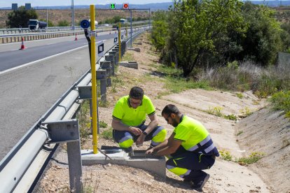 Dos operarios instalando ayer los soportes para el láser que delimitará los carriles de la autopista. 