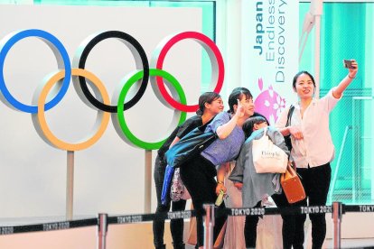 Viajeros haciendo fotos junto a los aros olímpicos, a su llegada al aeropuerto de Tokio.