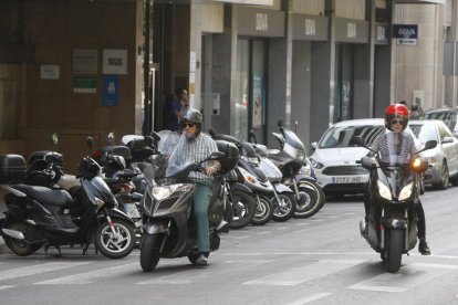 Dos motoristes i diversos vehicles aparcats a Lleida.