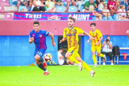 Juan Agüero persigue un balón con un rival al acecho.