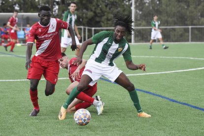 Un jugador de l’Alguaire protegint la pilota davant de dos rivals.