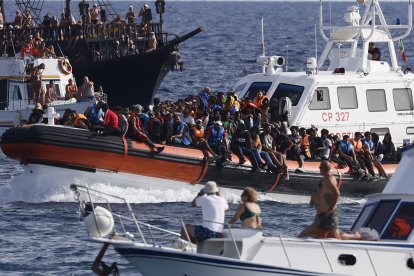 Turistes davant de migrants rescatats a Lampedusa, a Itàlia.