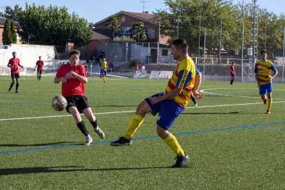 Un jugador del Bellpuig perllonga la pilota davant d’un rival a la zona ampla.