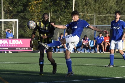 Un jugador del Lleida B refusa l’esfèric dins del cercle central davant la pressió d’un rival.