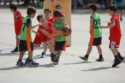 Un grup de nens juguen un partit de bàsquet.