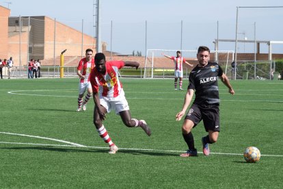 Un jugador del Gimenells juga la pilota davant la pressió d’un de l’Alcoletge.