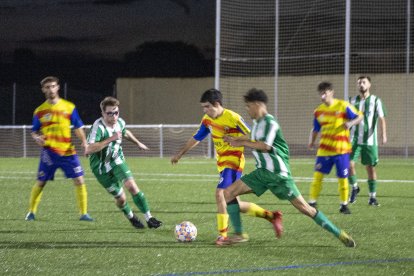 Un jugador del Bellpuig condueix la pilota davant la pressió de dos rivals.