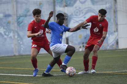 Un jugador de l’Alcarràs s’intenta escapolir de dos oponents de l’Alpicat.