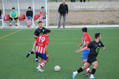 Un jugador del Pobla controla la pilota davant de l’atenta mirada del rival.