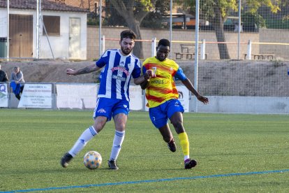 Un jugador de l’Organyà intenta controlar la pilota aguantant la pressió d’un futbolista del Bellpuig. 