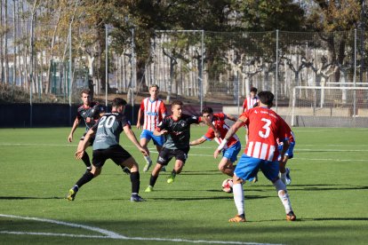 Nil Sauret intenta controlar una pilota envoltat de jugadors del Girona i al costat de Jordi Puig.